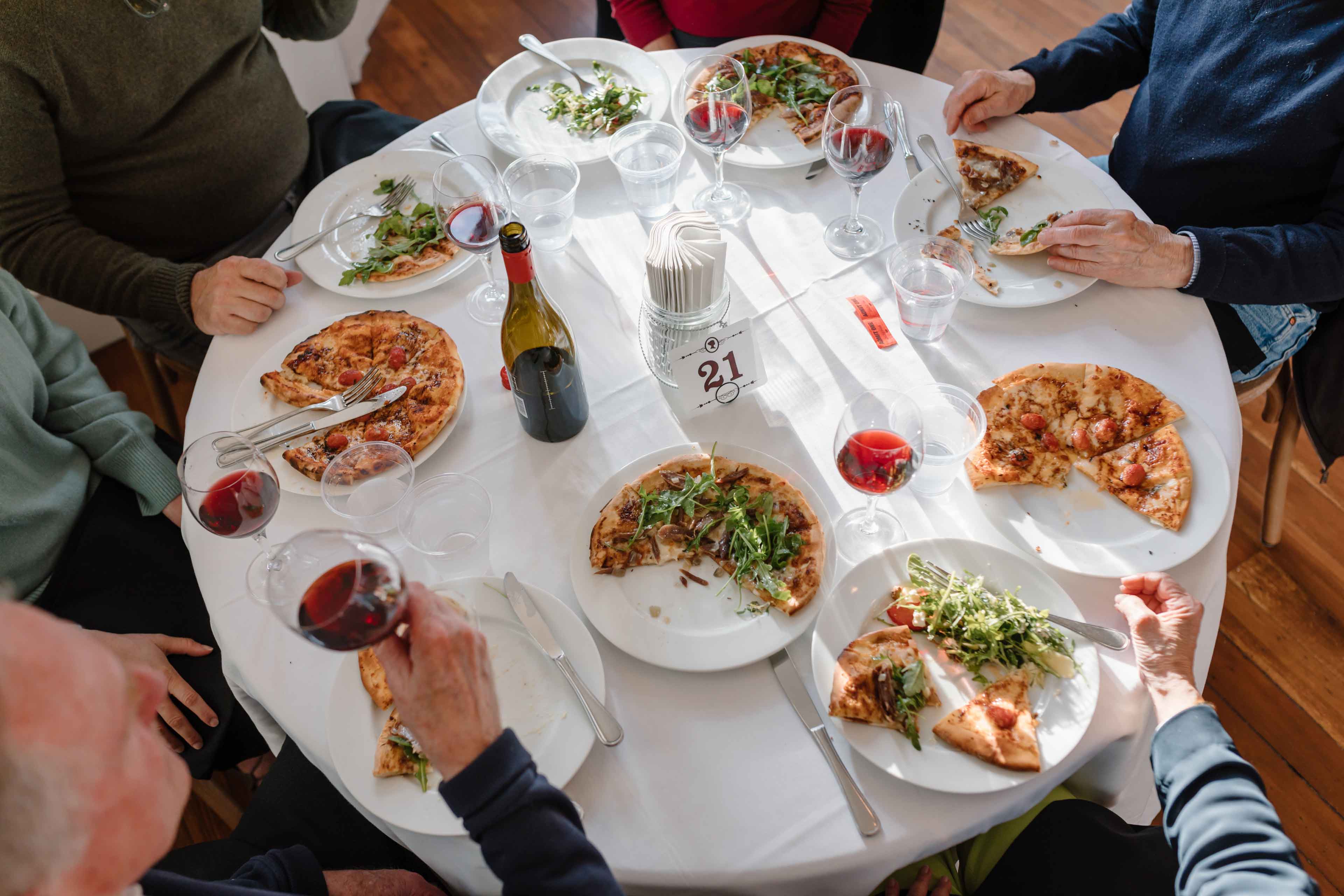 Overhead shot of guests enjoying pizza and wine at table